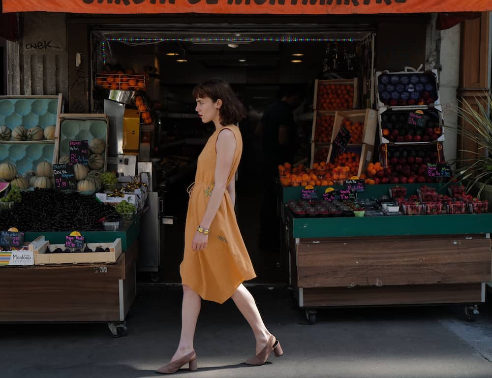 Girl walking in front of vegetables
